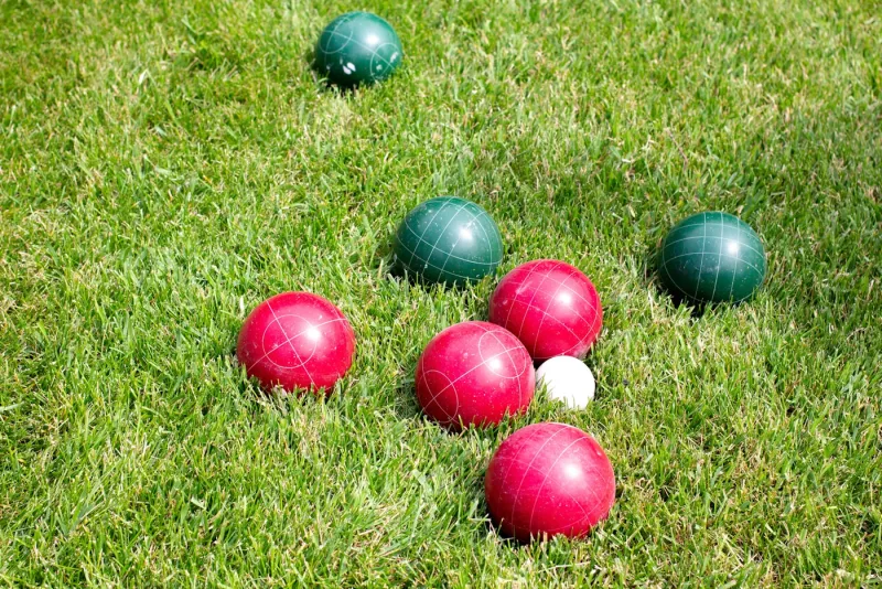Červené a zelené koule na pétanque ležící na zeleném trávníku