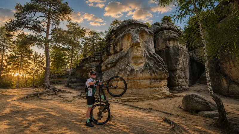 Cyklista u pískovcové skály s reliéfem na páteřní cyklotrase Kokořínskem